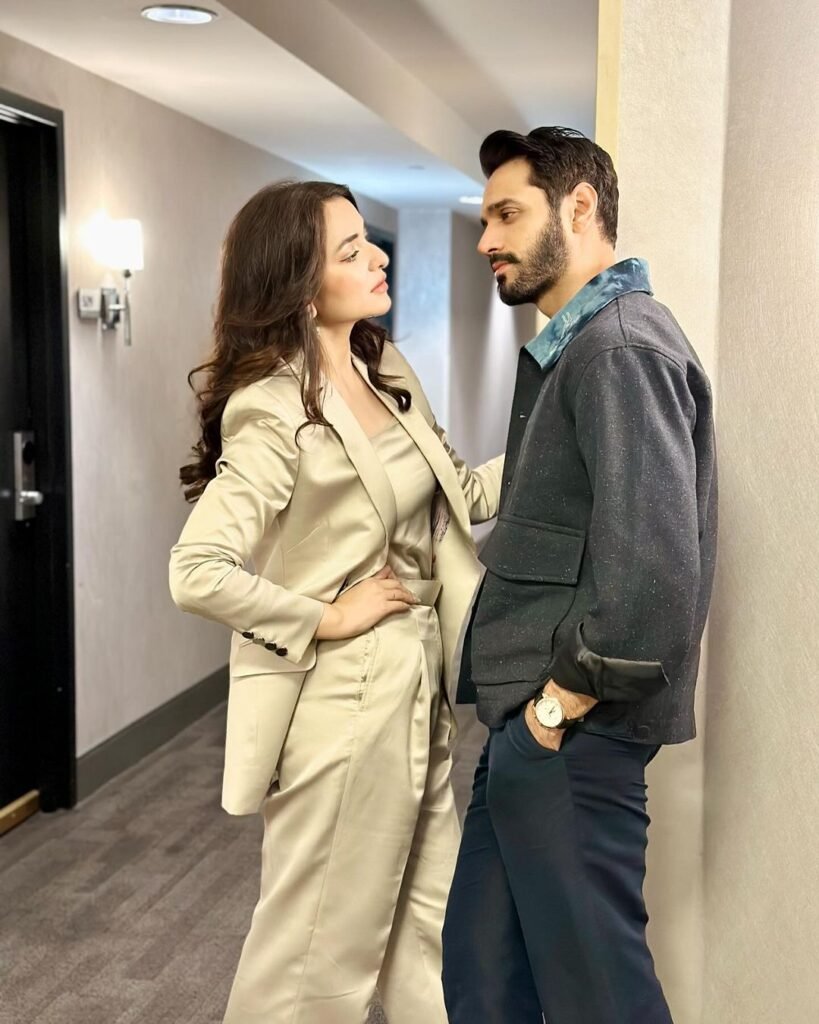 Yumna Zaidi and Wahaj Ali, standing side by side in a hallway with confident postures.