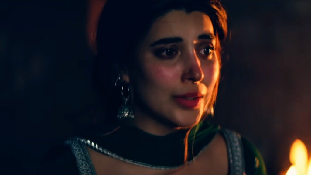 Urwa Hocane wearing traditional or formal attire with visible embellishments that suggest a metallic or shiny quality, possibly jewelry. A lit candle in the foreground provides a warm glow, creating an intimate and serene setting. The dark background adds to the moody and dramatic atmosphere of the photograph. This image captures Urwa Hocane in a moment of elegance and cultural richness, perfect for highlighting her presence in a sophisticated and artistic context.