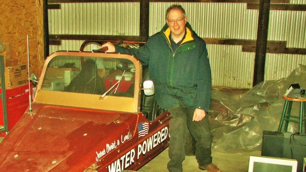 Stanley Meyer standing next to his water-powered car, showcasing his innovative water fuel cell technology.