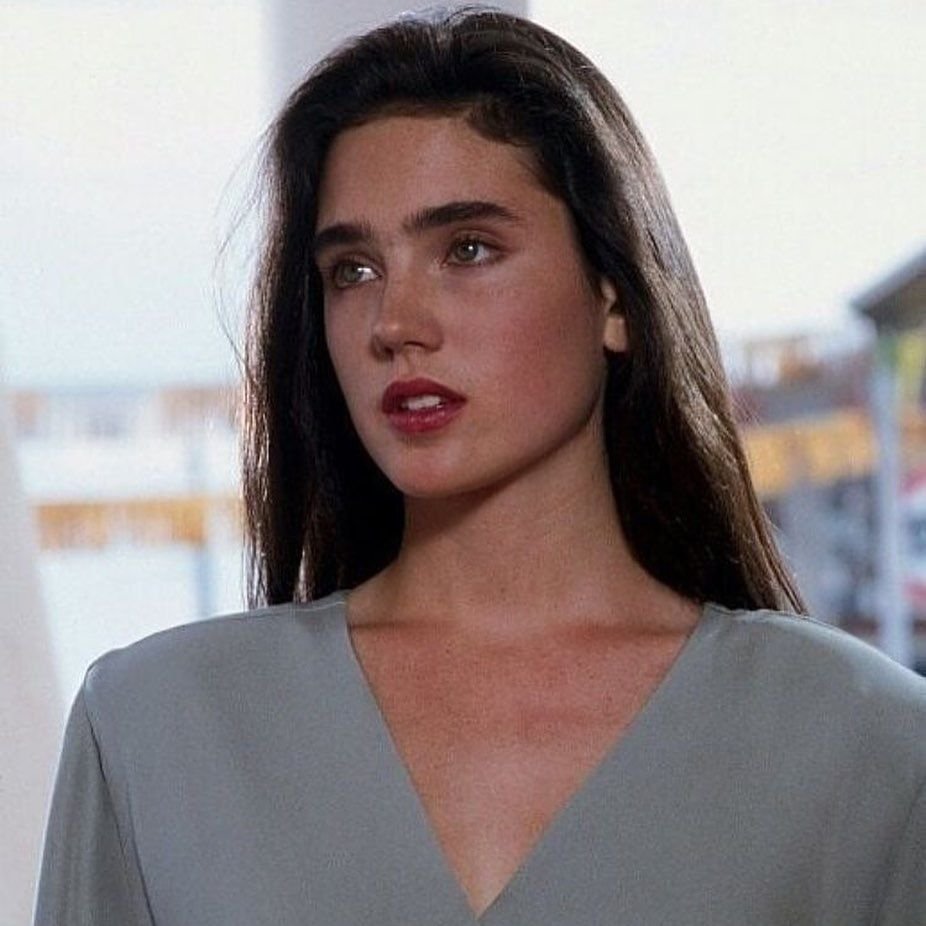 Image of a young Jennifer Connelly look-alike, long dark hair, wearing a grey v-neck top.