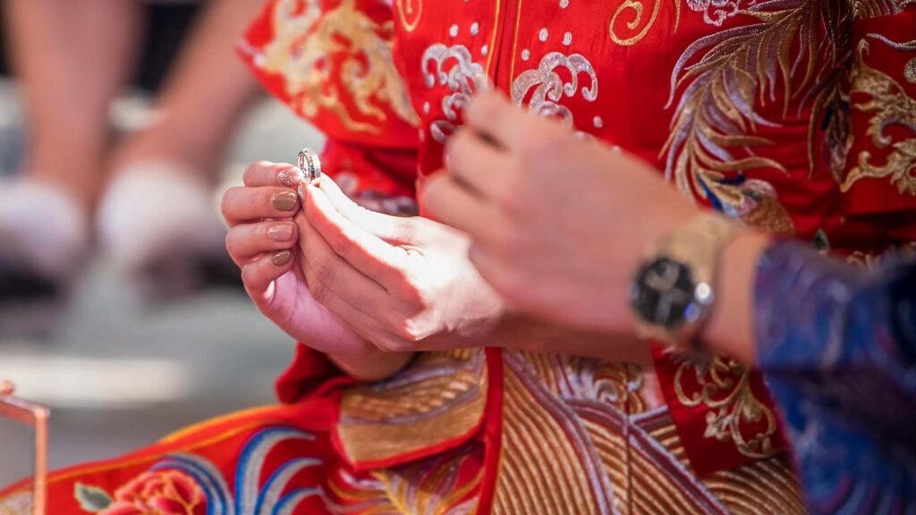 Bride and groom in Chinese wedding dresses were wearing rings for each other.