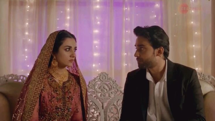 Sarah Khan and Bilal Abbas Khan sitting in a marriage hall and looking together a screenshot from Abdullahpur Ka Devdas